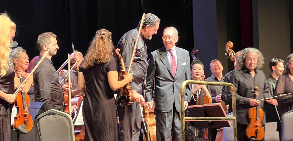 Foto en la que aparece el embajador junto a la orquesta en la tarima, durante el concierto de conmemoración de los 65 años de relaciones diplomáticas Colombia y Türkiye