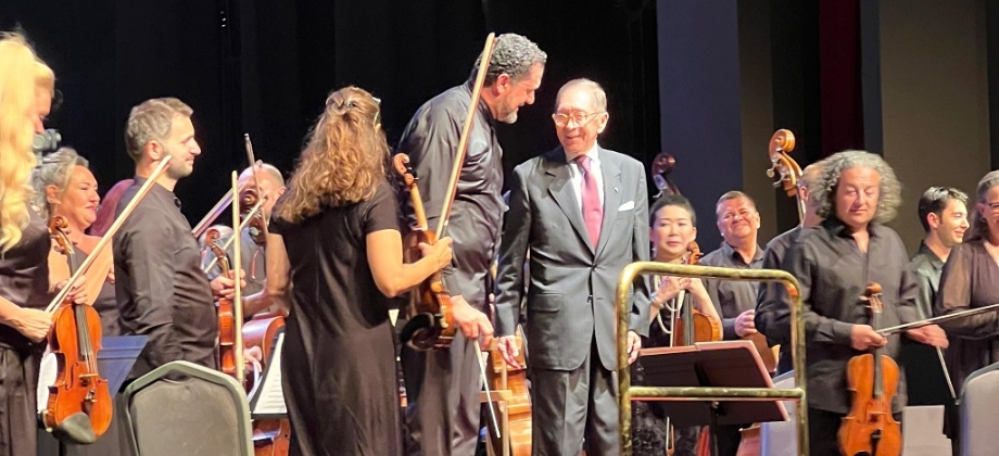 Foto en la que aparece el embajador junto a la orquesta en la tarima, durante el concierto de conmemoración de los 65 años de relaciones diplomáticas Colombia y Türkiye